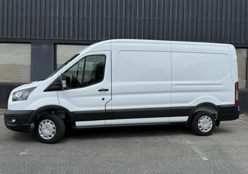 Vue de profil côté gauche d’un fourgon Ford Transit blanc avec bande noire basse et jantes tôles.