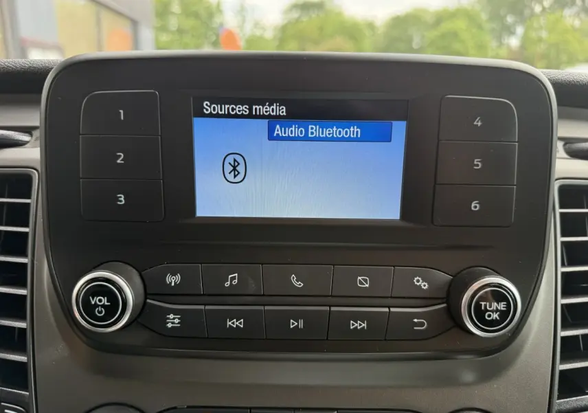 Écran central du Ford Transit Fourgon 2024 affichant la source audio Bluetooth, avec commandes et boutons autour.
