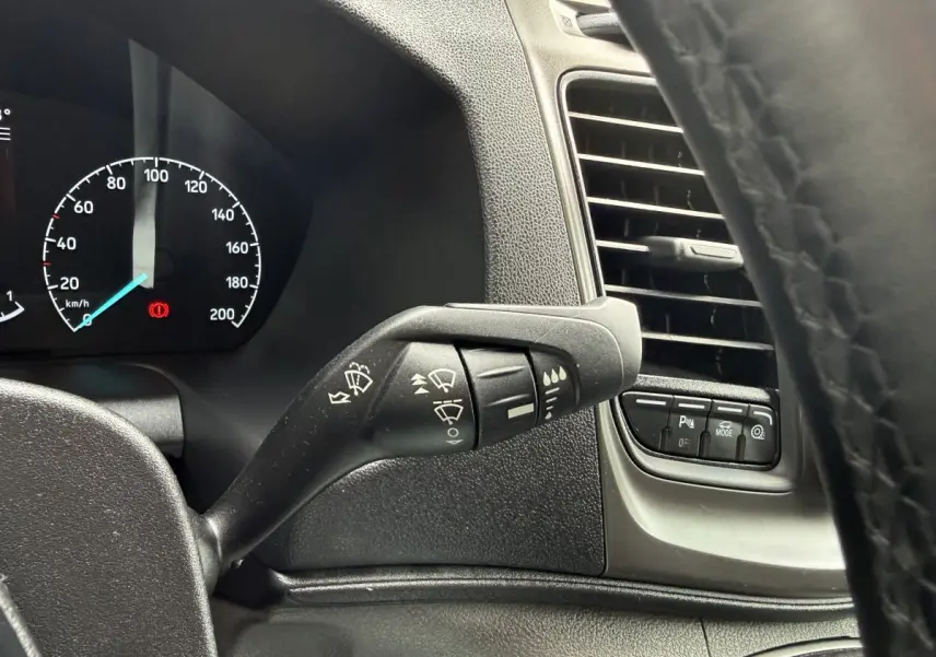 Vue intérieure rapprochée du levier d'essuie-glace et des commandes près de la ventilation du Ford Transit Fourgon 2024.