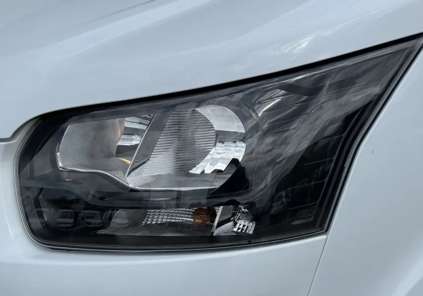 Gros plan sur le phare avant droit du Ford Transit Fourgon blanc 2024, mettant en valeur son design moderne.