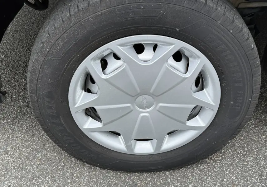 Gros plan sur la roue avant droite du Ford Transit Fourgon blanc, avec enjoliveur gris marqué du logo Ford.