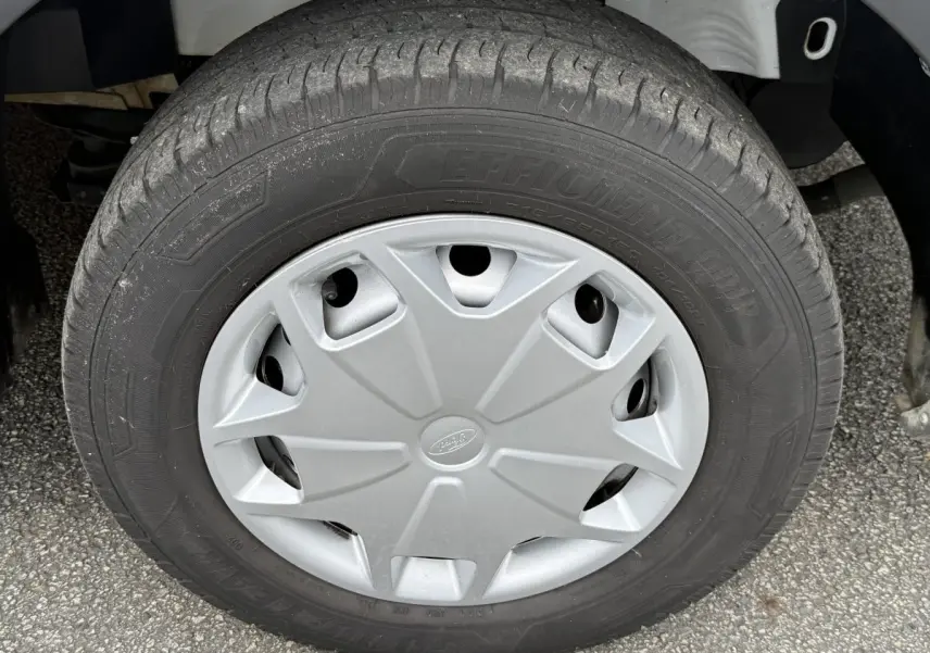Gros plan sur la roue avant droite du Ford Transit Fourgon blanc, avec enjoliveur gris marqué du logo Ford.