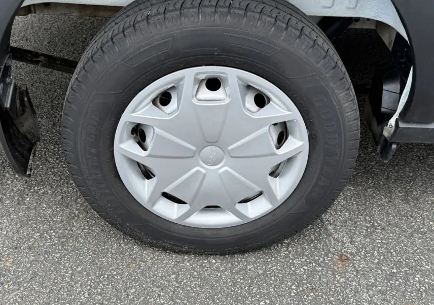 Gros plan sur la roue avant droite du Ford Transit Fourgon blanc, avec jante en acier et enjoliveur gris.