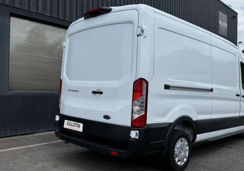 Vue 3/4 arrière droite d’un Ford Transit Fourgon blanc avec porte arrière pleine et pare-chocs noir.