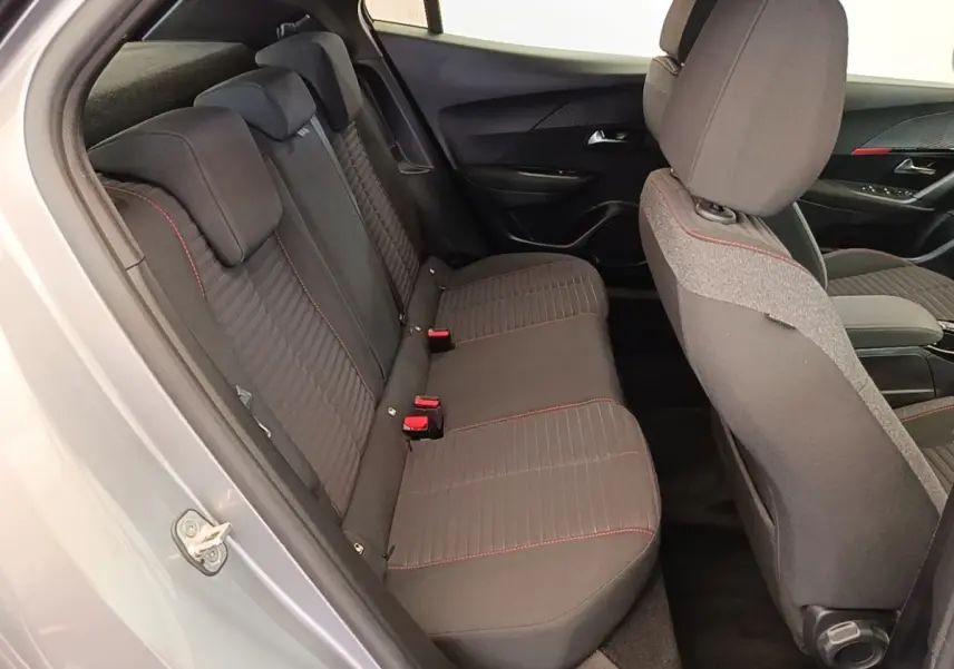 Vue intérieure côté gauche montrant la banquette arrière gris foncé avec surpiqûres rouges du Peugeot E-2008 électrique gris clair.
