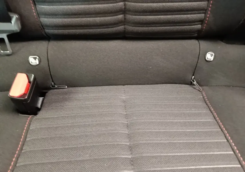 Gros plan sur la banquette arrière noire avec surpiqûres rouges et attaches Isofix du Peugeot E-2008 électrique.