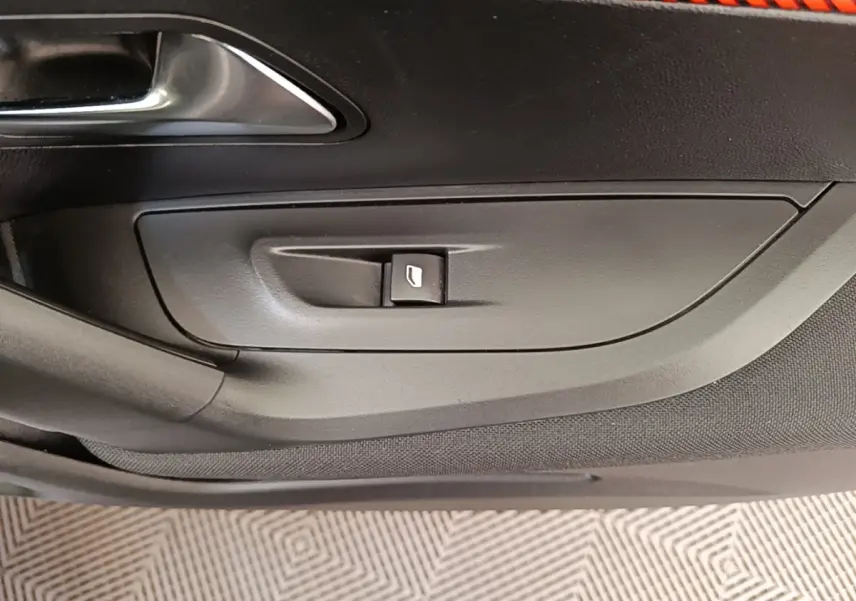Détail de la commande de lève-vitre côté gauche intérieur d'une Peugeot E-2008 électrique gris clair.