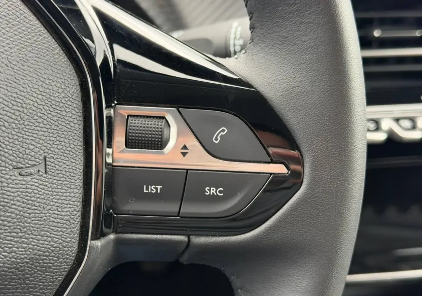 Gros plan sur les commandes noires du volant à droite du Peugeot 208 2025 Noir Perla Nera.