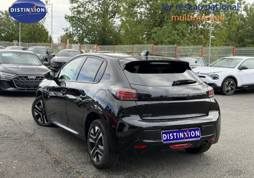 Vue 3/4 arrière droite d'une Peugeot 208 noire Perla Nera avec jantes alu, stationnée en extérieur.