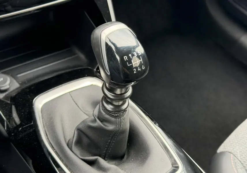 Gros plan sur le levier de vitesses manuel noir de la Peugeot 208 1.2 100ch Allure, intérieur tissu gris.