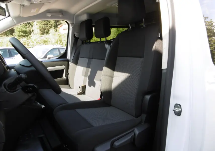 Intérieur du Peugeot Expert Long 2023 blanc, vue côté gauche sur les sièges avant en tissu noir et gris.
