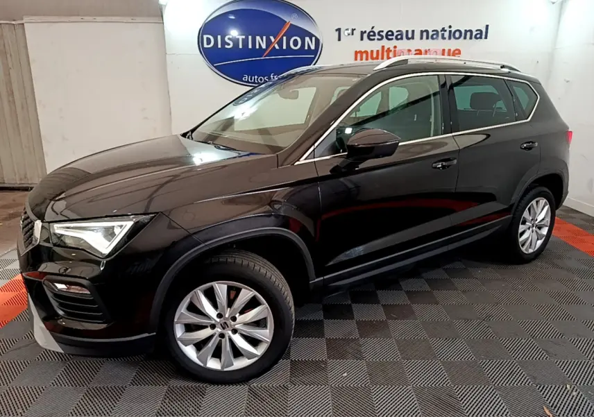 Vue 3/4 avant droite d'un SUV SEAT Ateca noir brillant, avec jantes alliage et barres de toit chromées en intérieur showroom.