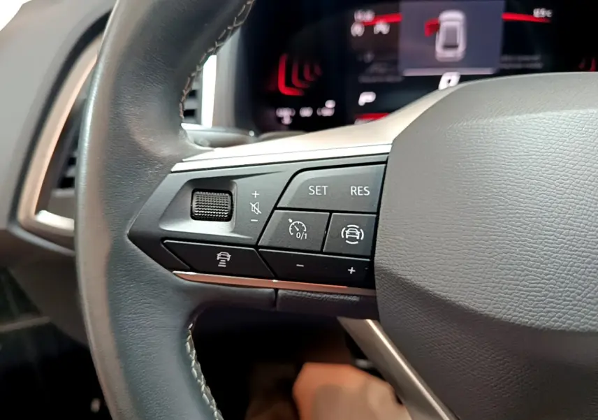 Gros plan sur le côté gauche du volant noir du SEAT Ateca 2022, avec commandes de régulateur de vitesse et assistance.