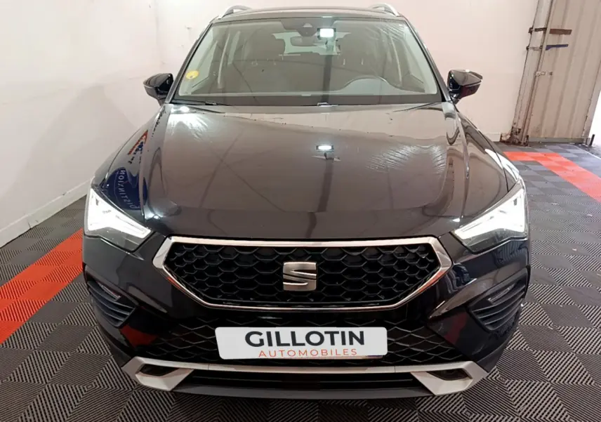 Vue frontale d'un SUV SEAT Ateca noir avec calandre hexagonale et phares LED allumés dans un garage.