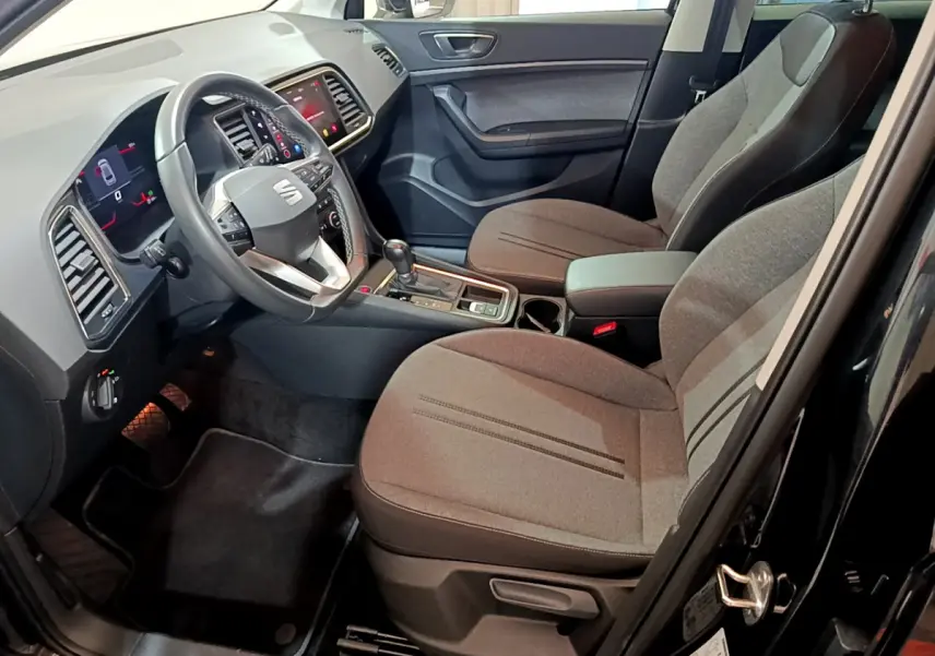 Intérieur avant droit du SEAT Ateca noir 2022, montrant sièges tissu gris, volant multifonction et écran tactile central.