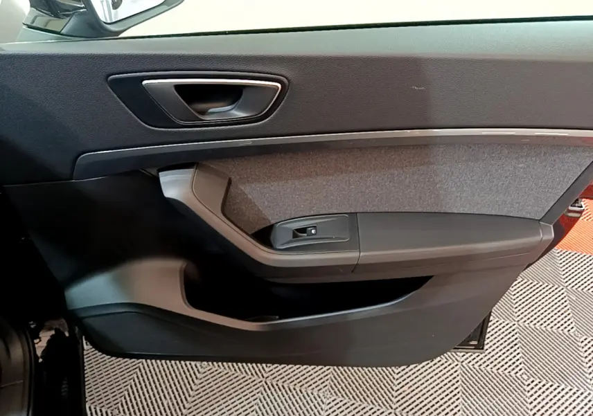Intérieur côté gauche de la porte avant d'une SEAT Ateca noire, avec garniture tissu et poignée argentée.