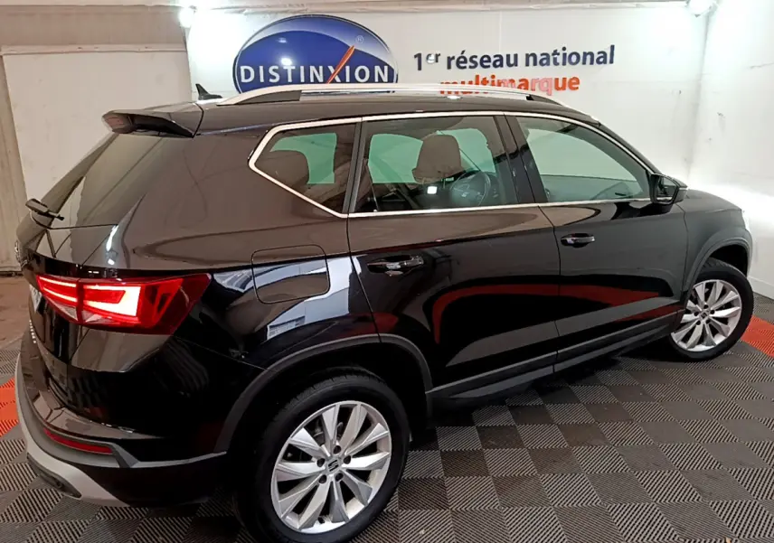 SEAT Ateca noir vue 3/4 arrière côté droit, feux arrière allumés et jantes alliage visibles en intérieur showroom