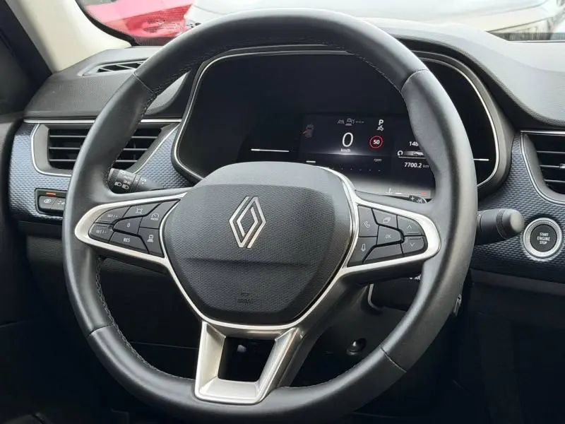 Vue rapprochée du volant noir du Renault Arkana 2025 avec tableau de bord numérique et bouton start/stop visible.