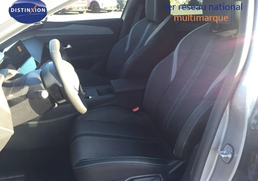 Vue intérieure côté conducteur de la Peugeot 308 gris Artense 2025, sièges en tissu noir avec surpiqûres contrastées.