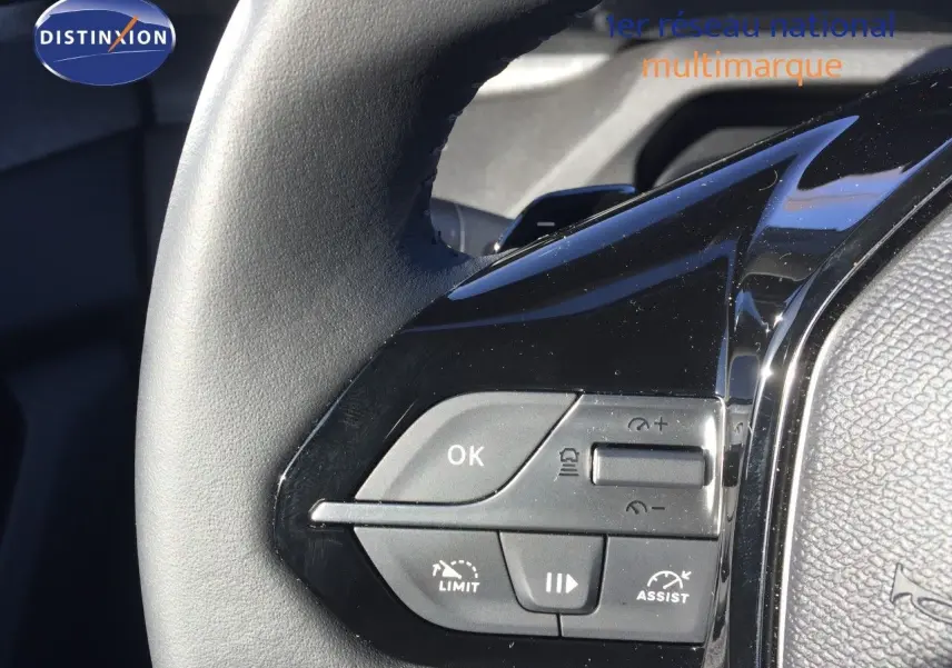 Gros plan sur les commandes au volant noir brillant de la Peugeot 308 gris Artense Hybrid 2025, côté gauche.