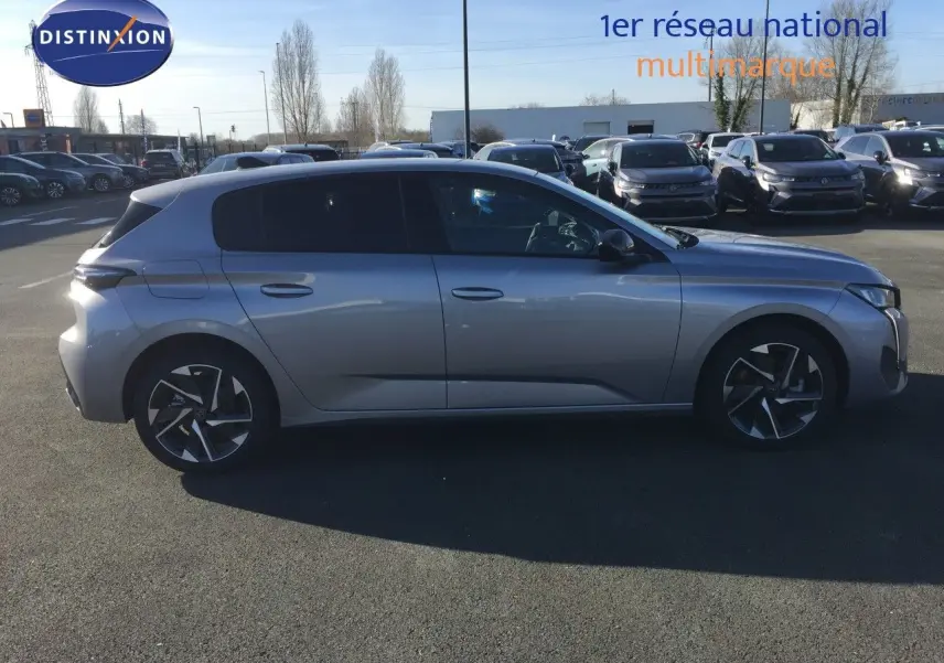 Peugeot 308 gris Artense métal vue de profil côté gauche sur parking avec jantes bi-ton et vitres teintées.