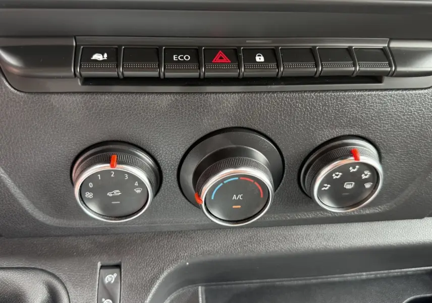 Gros plan sur les commandes de climatisation noires du tableau de bord du Renault Master blanc 2024.