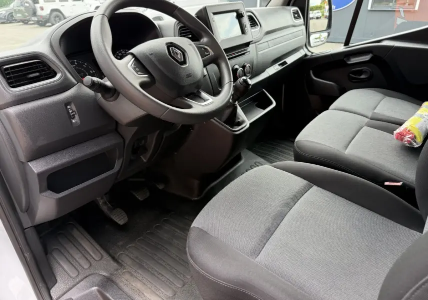 Intérieur du Renault Master 2024 vu côté conducteur, volant avec logo, sièges gris et tableau de bord avec écran tactile.