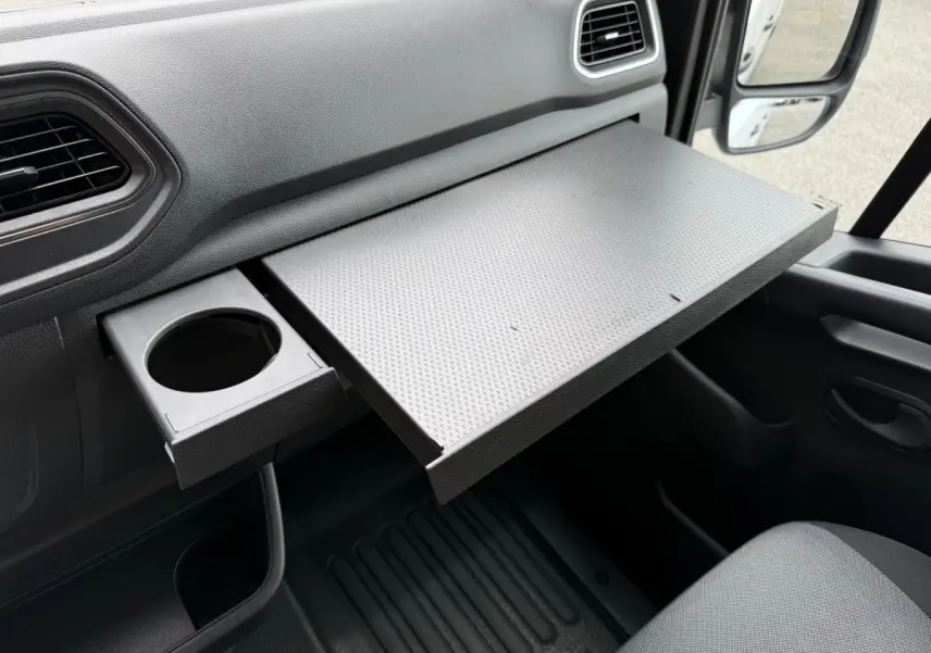Vue intérieure côté passager du Renault Master blanc 2024, mettant en valeur la tablette coulissante et porte-gobelet intégré.