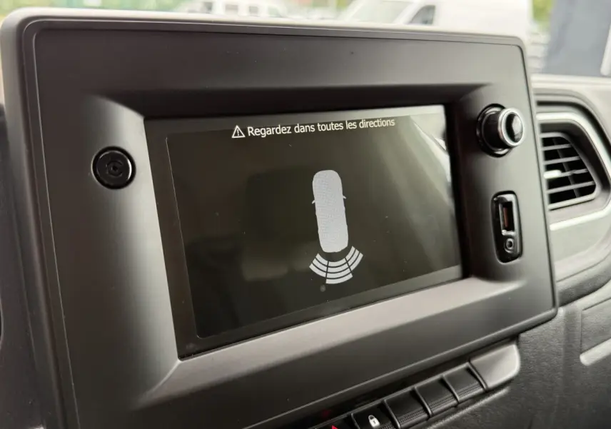Écran tactile central du tableau de bord du Renault Master blanc 2024 affichant l'aide au stationnement arrière.