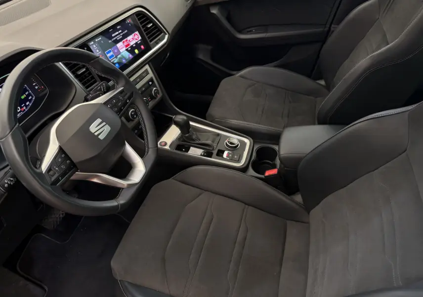 Intérieur du SEAT Ateca 2023 vu côté conducteur, sièges noirs, volant multifonctions et écran tactile central visible.