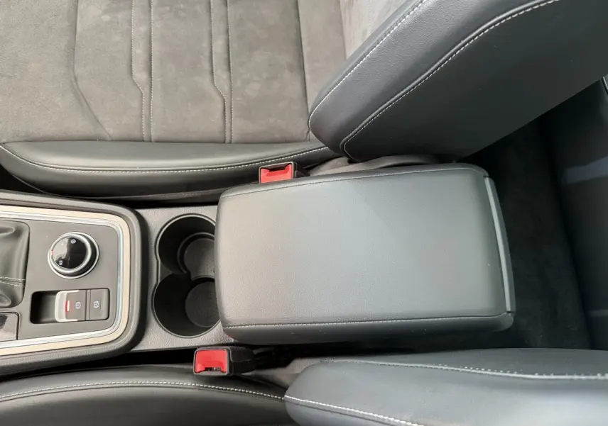 Vue plongeante sur la console centrale noire et les sièges gris clair du SEAT Ateca 2.0 TDI 2023 avec accoudoir fermé.