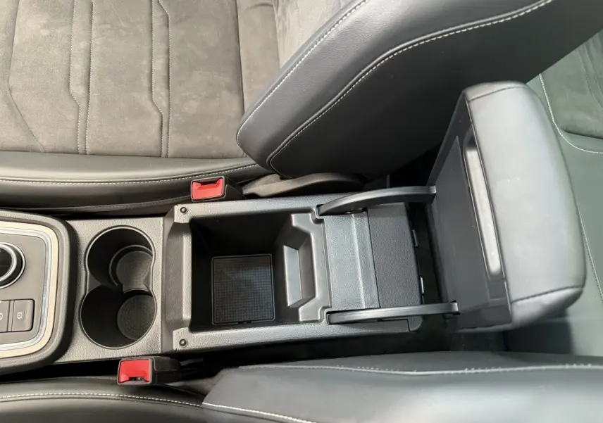 Vue plongeante sur l'accoudoir central noir ouvert et les porte-gobelets entre les sièges gris clair du SEAT Ateca 2023.