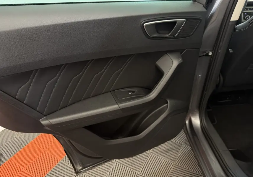 Vue rapprochée de la porte arrière gauche gris clair du SEAT Ateca 2023 avec garniture noire et bouton de fenêtre électrique.
