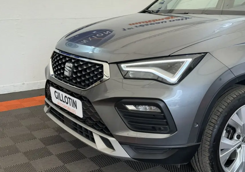 Vue 3/4 avant droit d'un SEAT Ateca gris clair avec calandre noire à motif losange et phares LED distinctifs.