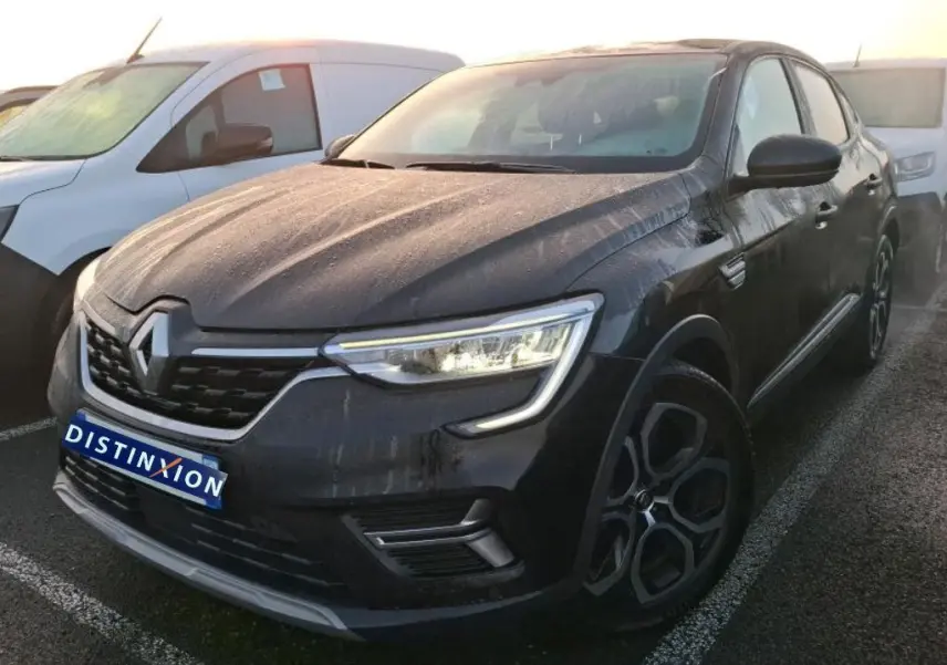 Vue 3/4 avant droit d’un Renault Arkana noir métal 2023 avec jantes bi-ton et calandre chromée, en intérieur showroom.