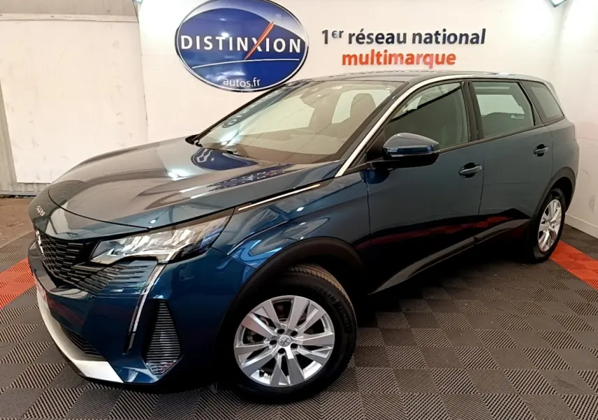 Peugeot 5008 bleu en 3/4 avant droit, avec calandre noire et jantes argentées, dans un showroom intérieur.