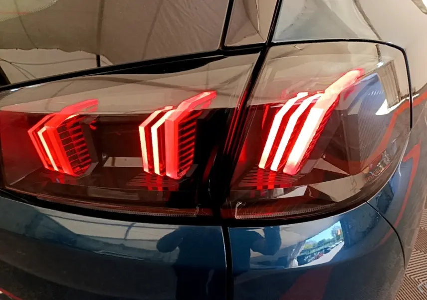 Gros plan sur les feux arrière allumés du Peugeot 5008 bleu, vue de l'angle arrière droit du véhicule.