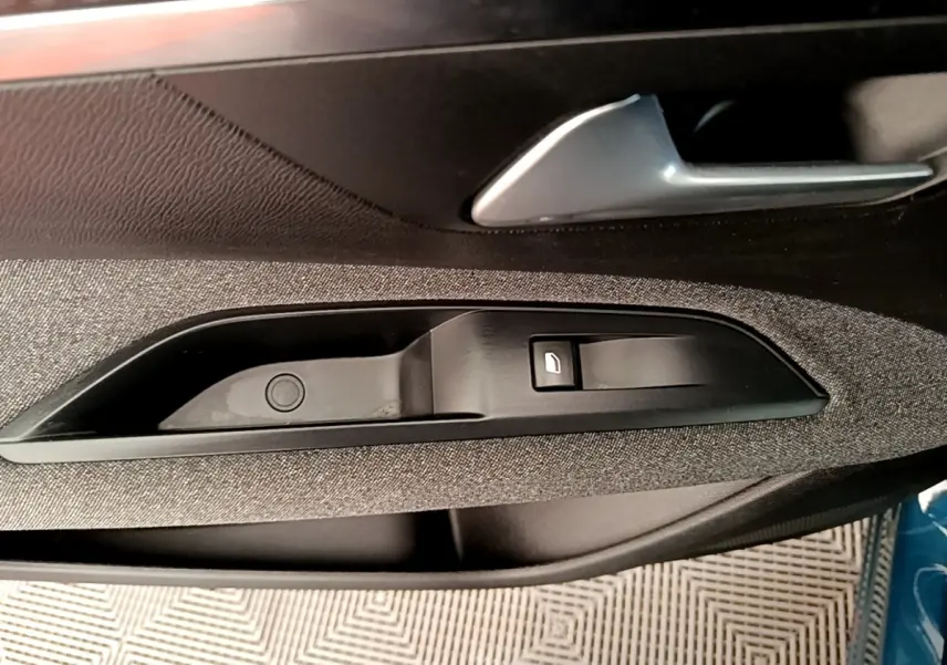 Détail de la poignée intérieure côté conducteur du Peugeot 5008 bleu, avec bouton de verrouillage et garniture textile grise.