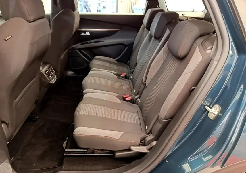 Vue latérale des sièges arrière gris du Peugeot 5008 bleu, montrant les trois places individuelles et l’espace intérieur.