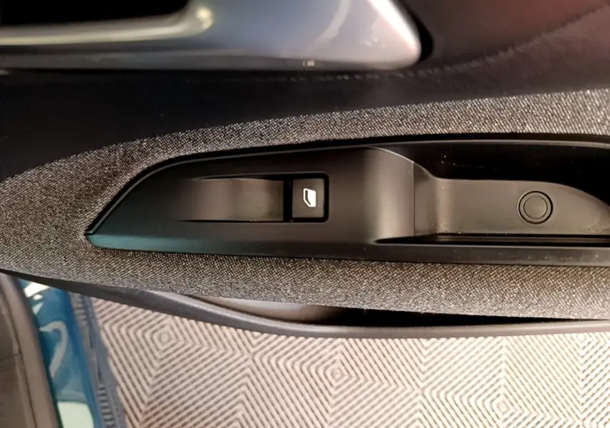 Gros plan sur la commande de lève-vitre côté conducteur dans l’habitacle du Peugeot 5008 bleu.