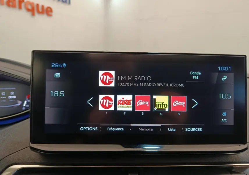 Écran tactile central affichant la radio FM dans l'habitacle du Peugeot 3008 rouge, vue intérieure frontale.
