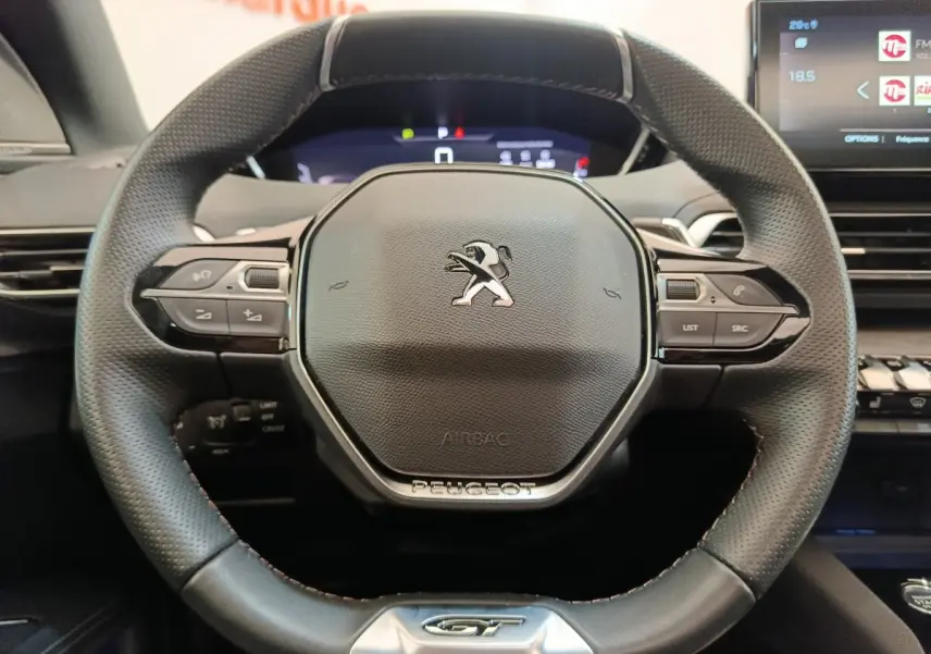Vue rapprochée du volant cuir perforé Peugeot 3008 GT Pack 2022 avec commandes multifonctions et logo central.