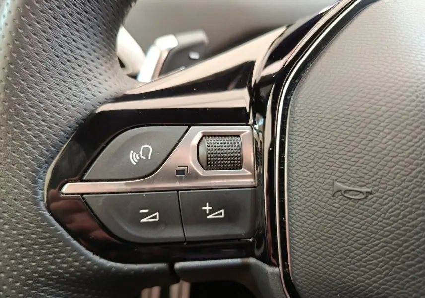 Gros plan sur les commandes vocales et volume du volant cuir noir du Peugeot 3008 GT Pack 2022.