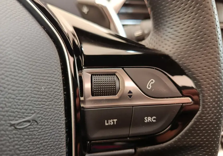 Gros plan sur les commandes noires du volant perforé du Peugeot 3008 GT Pack 2022, côté gauche.