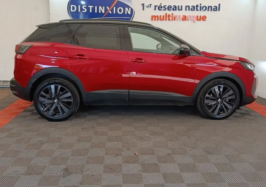 Vue latérale droite d'un Peugeot 3008 rouge 2022 avec jantes noires et toit noir, en intérieur showroom.