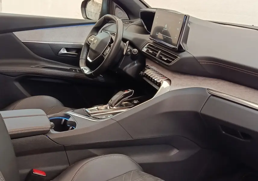 Vue intérieure côté conducteur du Peugeot 3008 GT Pack 2022, tableau de bord moderne avec écran tactile et volant cuir noir.