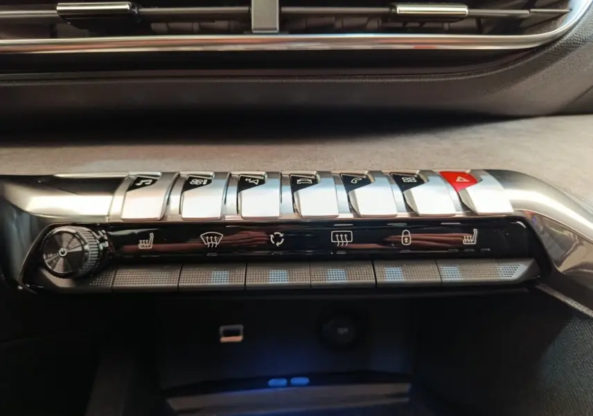 Gros plan sur la console centrale du Peugeot 3008 rouge 2022, montrant les commandes climatisation et boutons piano chromés.