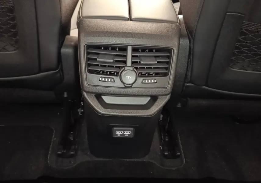 Vue rapprochée de la console centrale arrière noire du Peugeot 3008 2022 avec ventilation et prises USB visibles.
