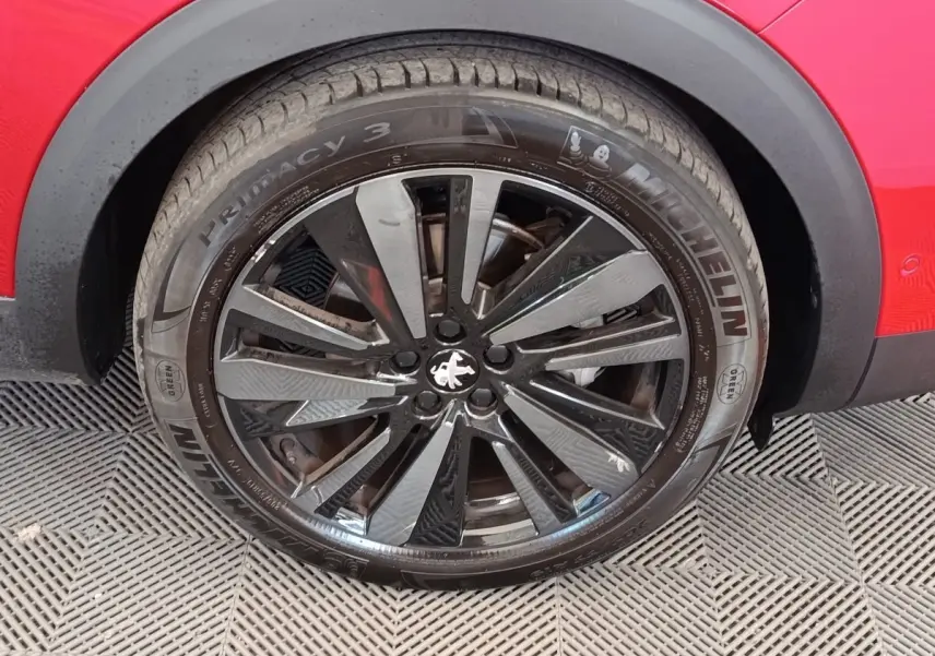 Gros plan sur la roue avant droite noire et argentée du Peugeot 3008 rouge, avec pneu Michelin visible.
