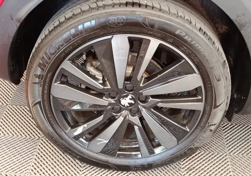 Gros plan sur la jante alliage noire et argentée du PEUGEOT 3008 rouge, avec logo lion au centre.